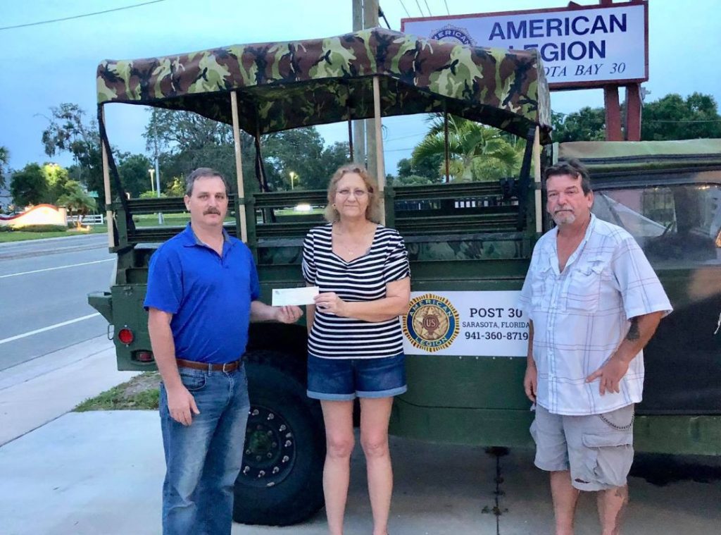 A community member receiving a check from representatives at American Legion Post 30 in Sarasota, Florida, illustrating the local veteran organization network that supports Sarasota County veterans alongside SRQ Vets.